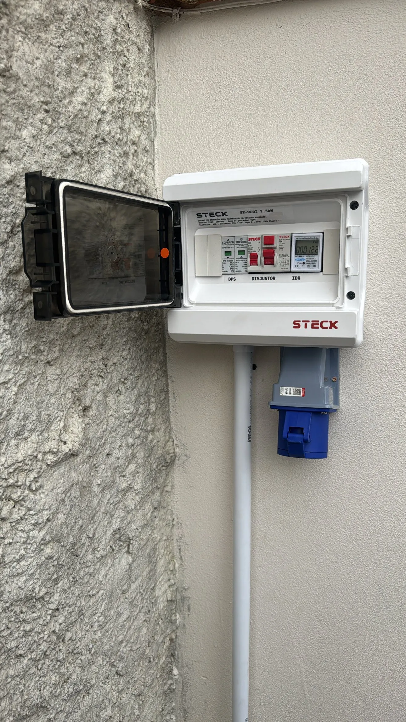 Quadro de proteção aberto com disjuntores, instalado em parede externa