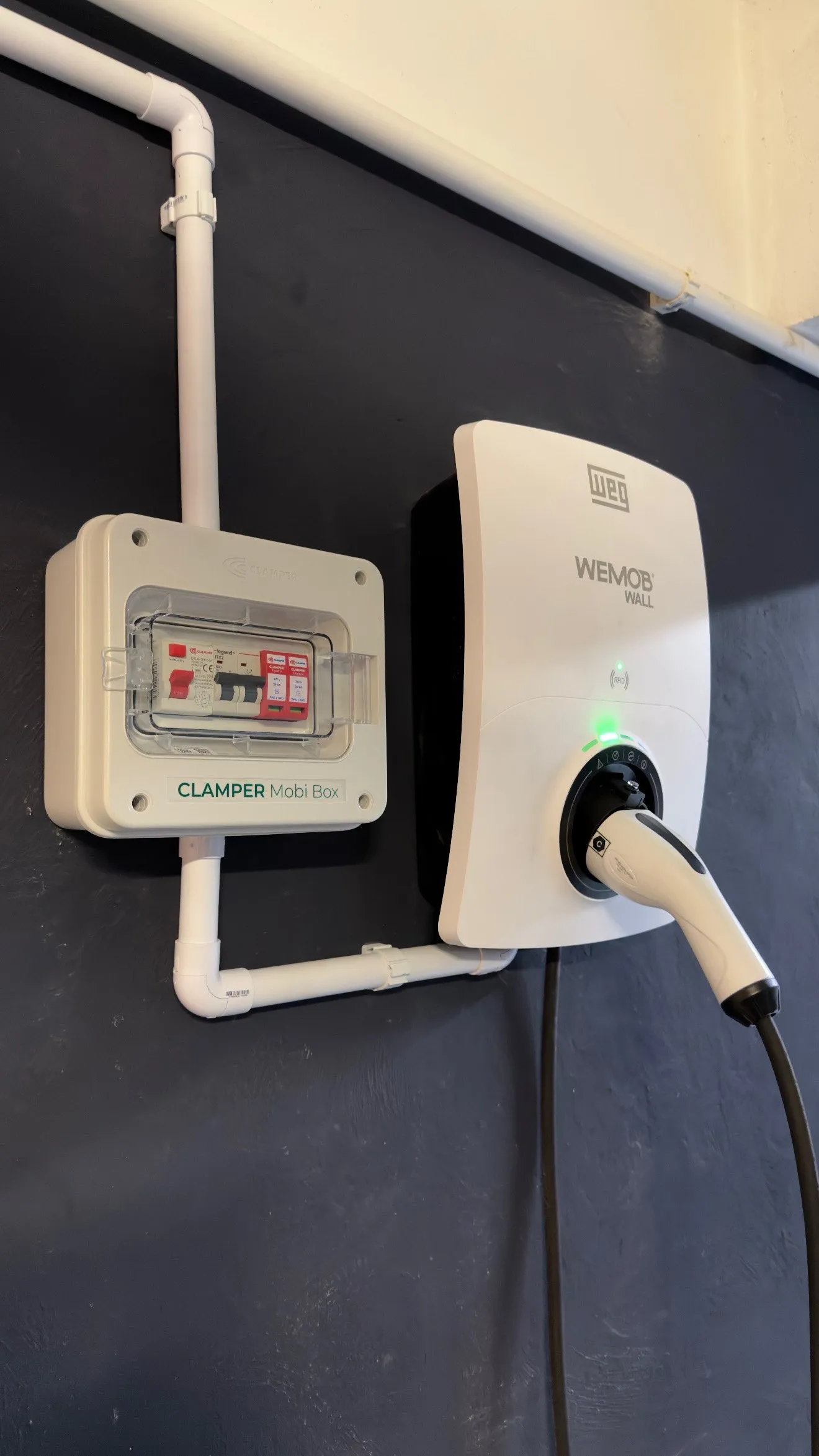 Carregador wallbox instalado em parede escura com quadro de proteção dedicado, em instalação da GKN Watts